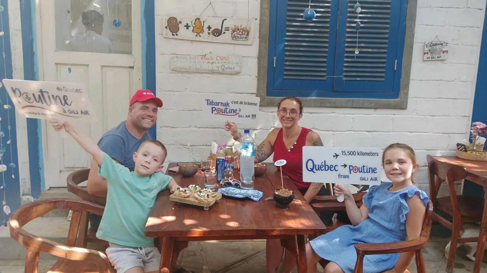 Parents and children enjoying their meal with Poutine Gili Air signs