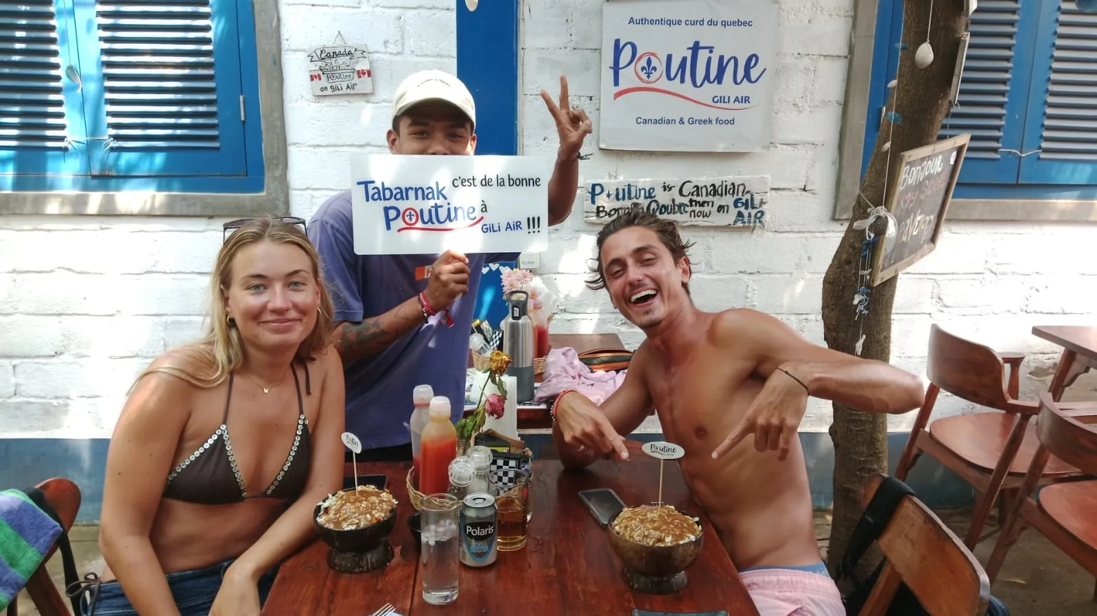 Friends having fun with Poutine signs over bowls of poutine